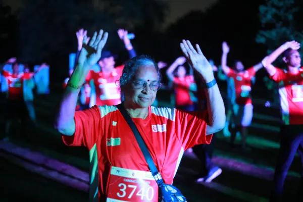 Older woman dancing with arms up in the pre-dawn warm-up