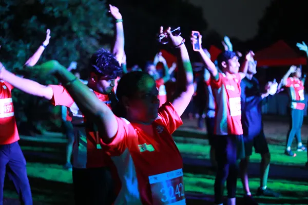 Arms-up warm-up crowd under colour lights